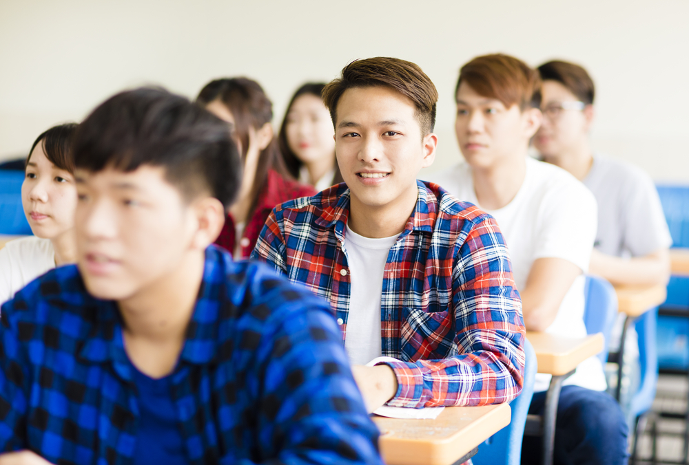 smiling male college student sitting  with classmates