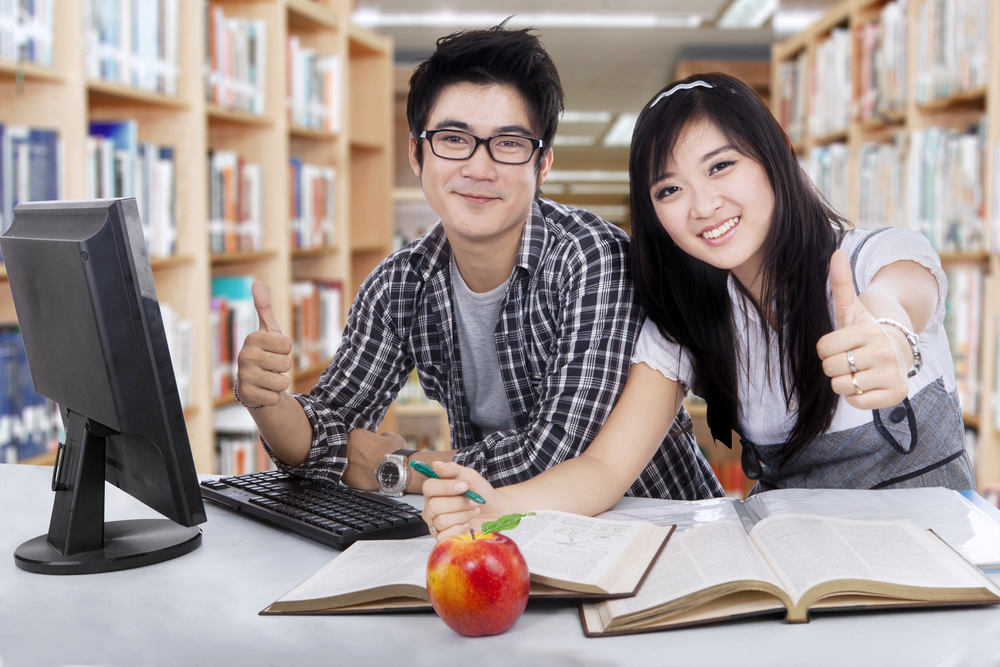 Students showing thumbs up in library